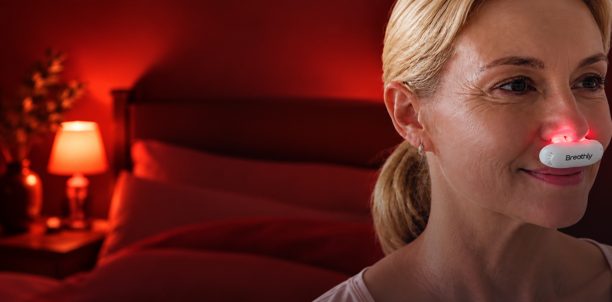 Woman using the Breathly Comfort red-light nasal device at night in a warmly lit bedroom